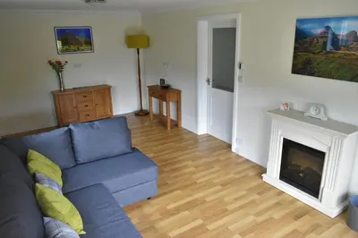 a living room with a blue couch and a fireplace at Hawthorn Cottage in Glencoe