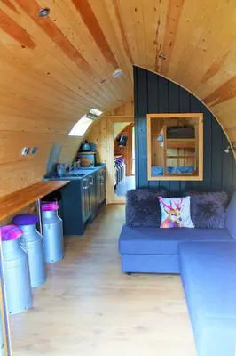 a living room with a blue couch in a tiny house at Cairnfold Cabins in Kilsyth