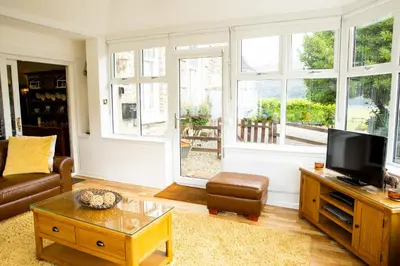 a living room with a couch and a tv and windows at Rhumhor House in Carrick