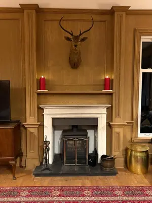 a living room with a fireplace with a deer head on the wall at Rhumhor House in Carrick