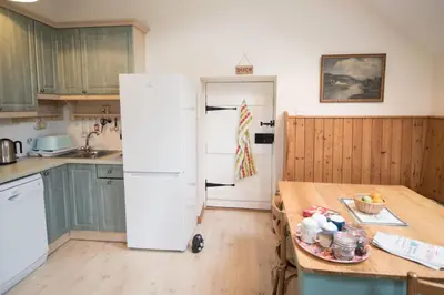 a kitchen with a white refrigerator and a table at Coachmans Bothy - 50m from the beach in Port Appin