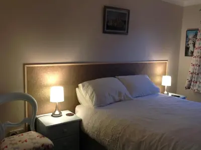 a bedroom with a bed with two lamps and a chair at Saorsa House Culross in Fife