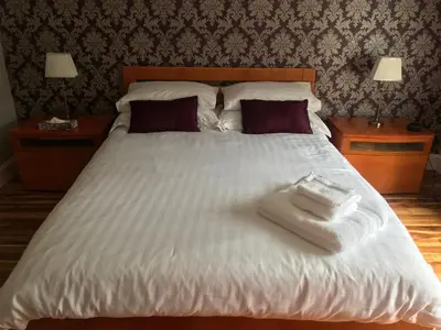 a large white bed with two towels on it at The Neuk in Uphall