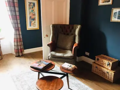 a living room with a chair and a table at Chefs cottage in Kenmore