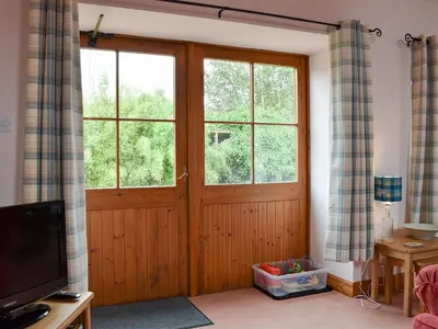 a room with a wooden door and two windows at The Cottage At Cauldcoats in Linlithgow