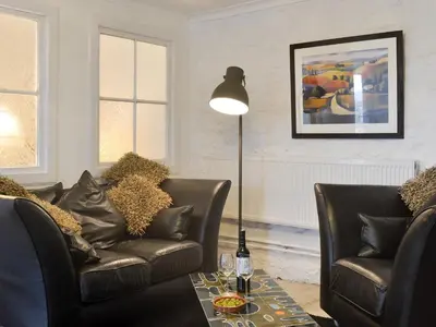 a living room with two leather chairs and a lamp at The Calving Shed in Neilston