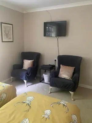 a bedroom with two chairs and a bed and a tv at Sir Andrew Murray House in Strathyre