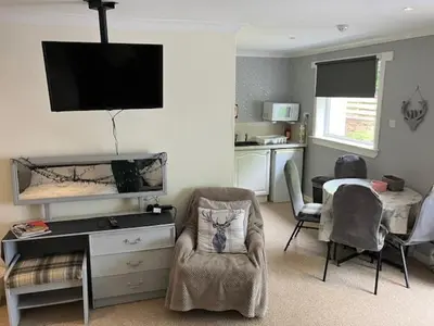 a living room with a tv and a table and chairs at Sir Andrew Murray House in Strathyre