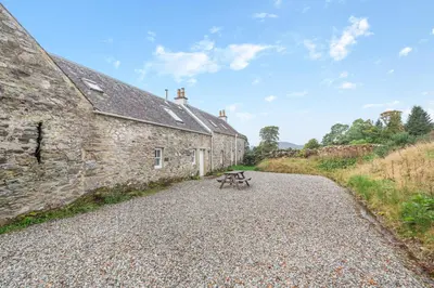 a picnic table in front of a stone building at Inverglen Farm in Strachur