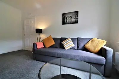 a living room with a blue couch and a glass table at Signature - Shawburn House in Hamilton