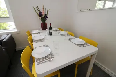 a dining room table with yellow chairs and a white tablecloth at Signature - Belhaven House in Hamilton