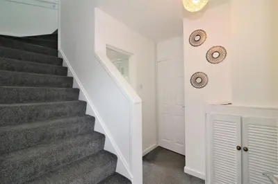 a staircase in a home with white walls and gray carpet at Signature - Belhaven House in Hamilton