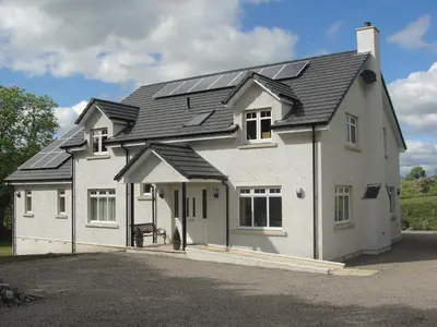 a white house with solar panels on the roof at Dunroamin in Drymen