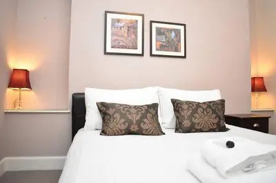 a white bed with two pillows and two pictures on the wall at West Port - 2BR in the heart of the old town just off the Grassmarket in Edinburgh