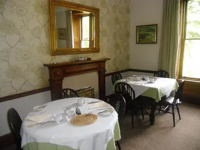 a dining room with two tables and a mirror at Ormidale Hotel in Brodick
