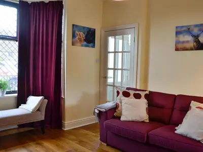 a living room with a purple couch and a window at Curlew Cottage in Creetown