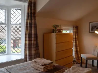 a bedroom with a bed and a dresser and a window at Curlew Cottage in Creetown