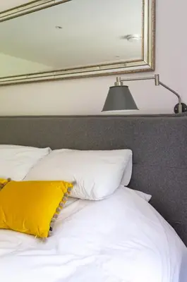 a bed with a yellow pillow and a mirror at Castle View Luxury 1 Bed Apartment in Edinburgh