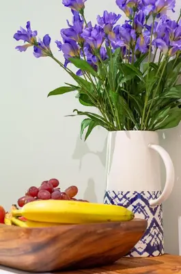 a vase with purple flowers and a wooden bowl with a banana at Castle View Luxury 1 Bed Apartment in Edinburgh