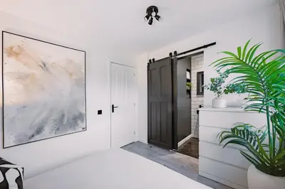 a bedroom with a black door and a potted plant at Emirates ApartHOUSE in Glasgow