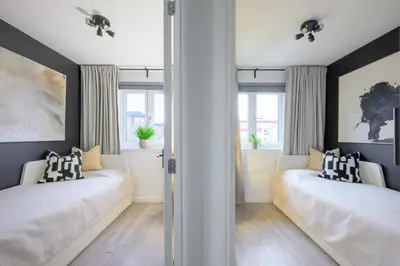 two beds in a room with two windows at Emirates ApartHOUSE in Glasgow