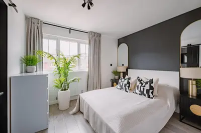 a bedroom with a white bed and two plants at Emirates ApartHOUSE in Glasgow
