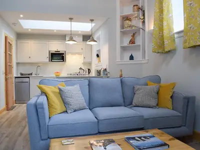 a blue couch in a living room with a kitchen at The Old Stables At Westerton in Crieff