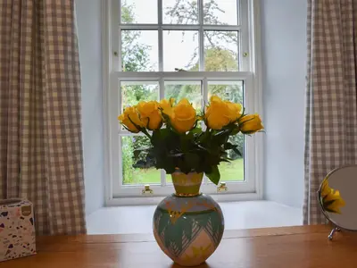 a vase filled with yellow roses sitting on a table at The Old Stables At Westerton in Crieff
