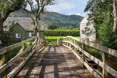 a bridge over a road with a house on it at Enchanting,rustic, Dundurn Mill with stunning views and private river in Comrie