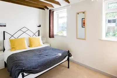 a bedroom with a bed and two windows at Altquhur Byre in Drymen