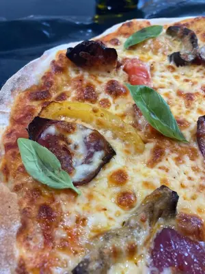 a pizza with basil leaves on top of it at Altquhur Byre in Drymen