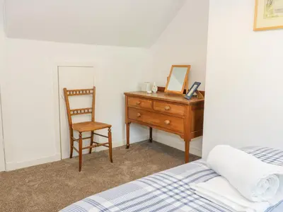 a bedroom with a bed and a dresser and a chair at Daisy Cottage in Moffat
