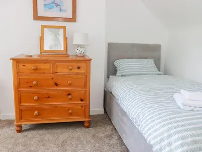 a bedroom with a bed and a dresser with a picture on it at Daisy Cottage in Moffat