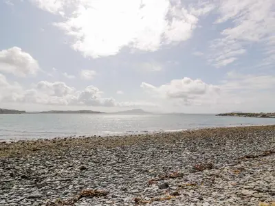 a rocky beach with the ocean in the background at Grebe Cottage in Oban