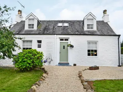 a white house with a green door at Altbeg in Brodick