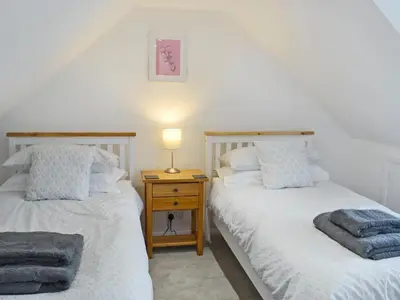 two twin beds in a room with a night stand at Altbeg in Brodick