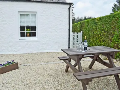 a wooden picnic table with a bottle of wine on it at Altbeg in Brodick