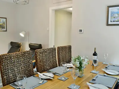 a dining room table with chairs and a bottle of wine at Altbeg in Brodick
