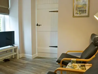 a living room with a chair and a television at Altbeg in Brodick