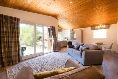 a living room with two couches and a living room with at Deerstalker Lodge cozy lodge with wood burner in Crianlarich