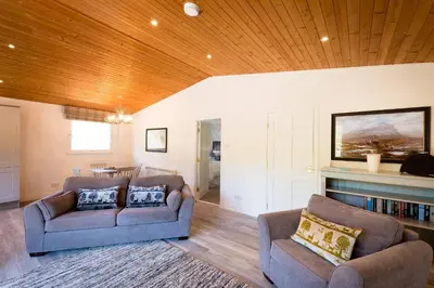 a living room with two couches and a fireplace at Deerstalker Lodge cozy lodge with wood burner in Crianlarich