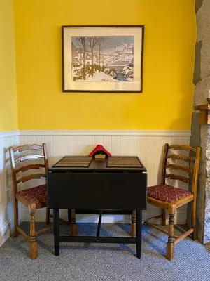 a table and two chairs in front of a yellow wall at Holly Cottage in Glencoe