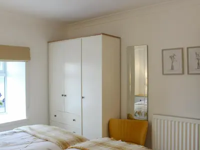 a bedroom with a white cabinet and a bed at Rhunahaorine Cottage in Gortinanane