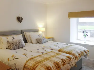 a bedroom with a bed with a blanket on it at Rhunahaorine Cottage in Gortinanane