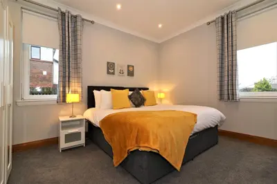 a bedroom with a large bed with two windows at Signature - Greenlees Clubhouse 3 Bed in Cambuslang