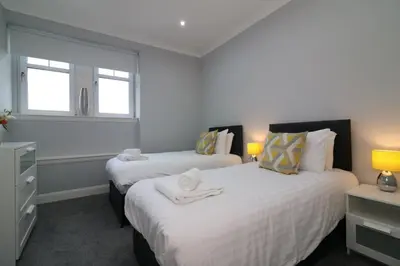 two beds in a small room with two windows at Signature - Greenlees Clubhouse in Glasgow