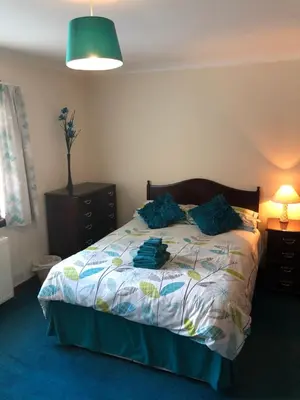 a bedroom with a bed with blue pillows on it at Inveroran in Campbeltown