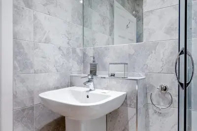 a bathroom with a white sink and a shower at Heart of Edinburgh City Centre 3 Bed Georgian Apt in Edinburgh
