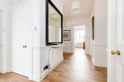 a hallway with a mirror and white walls at Heart of Edinburgh City Centre 3 Bed Georgian Apt in Edinburgh