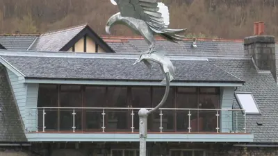 a statue of a bird on a pole in front of a house at Highland Getaway in Kinlochleven